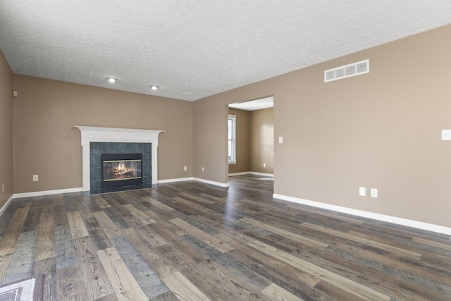 unfurnished living room with a tile fireplace, a textured ceiling, and dark hardwood / wood-style flooring