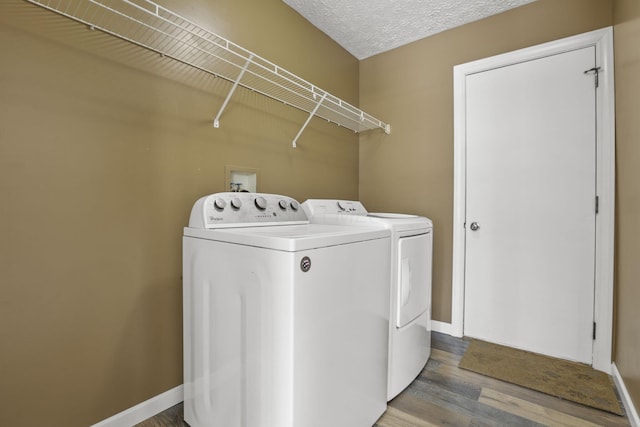 clothes washing area with wood-type flooring, washing machine and clothes dryer, and a textured ceiling