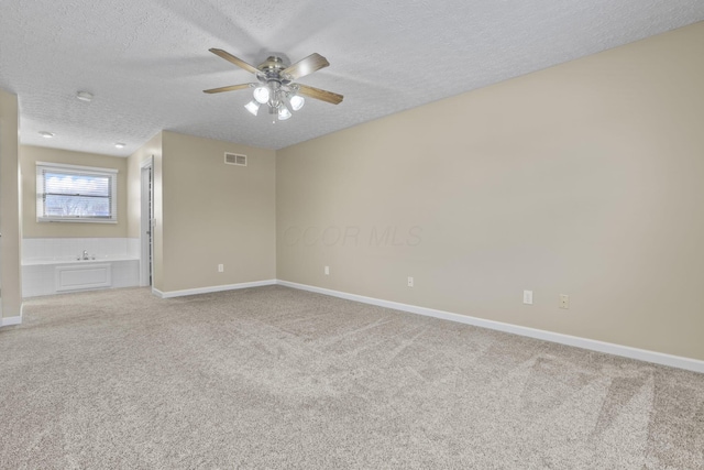 spare room with ceiling fan, a textured ceiling, and carpet flooring