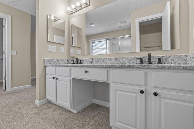 bathroom with vanity, an enclosed shower, and a textured ceiling