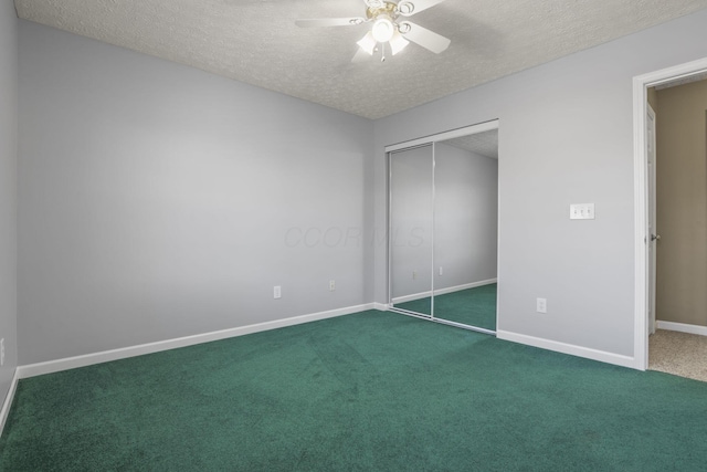 unfurnished bedroom with ceiling fan, a closet, a textured ceiling, and dark colored carpet