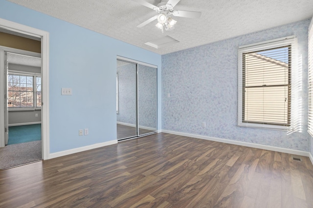 unfurnished bedroom featuring dark wood-type flooring, a textured ceiling, ceiling fan, and a closet