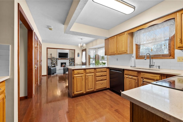 kitchen with dishwasher, sink, hanging light fixtures, tasteful backsplash, and kitchen peninsula