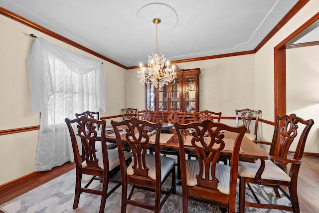 dining space with crown molding, hardwood / wood-style floors, and a notable chandelier