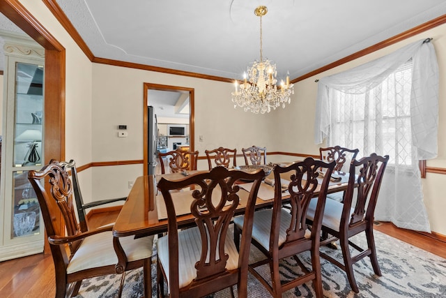 dining area with crown molding, a notable chandelier, and hardwood / wood-style flooring