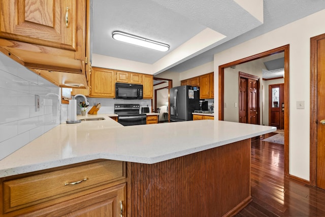 kitchen featuring sink, backsplash, kitchen peninsula, a textured ceiling, and black appliances