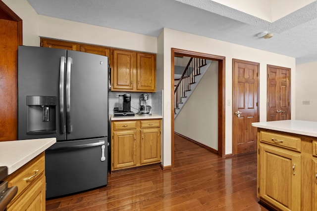 kitchen with tasteful backsplash, stainless steel fridge, dark hardwood / wood-style flooring, and a textured ceiling