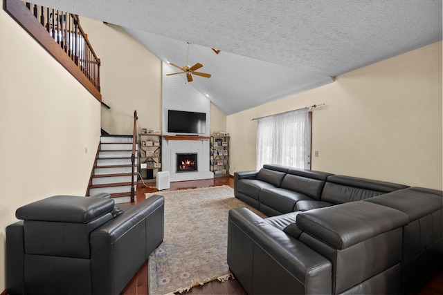 living room with a textured ceiling, ceiling fan, dark hardwood / wood-style floors, and a fireplace