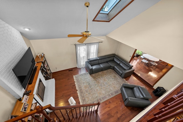 living room with ceiling fan, dark hardwood / wood-style flooring, and lofted ceiling with skylight