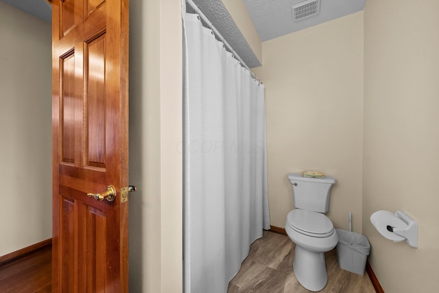 bathroom featuring hardwood / wood-style floors, a textured ceiling, and toilet