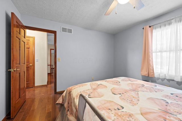 bedroom with wood-type flooring, a textured ceiling, and ceiling fan