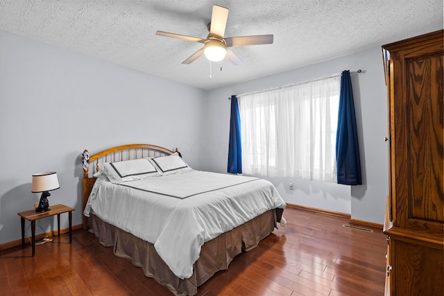 bedroom with ceiling fan, dark hardwood / wood-style flooring, and a textured ceiling