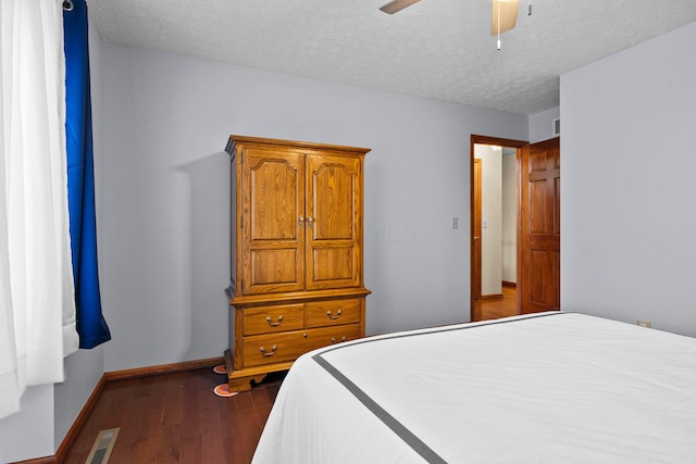 bedroom with a textured ceiling, ceiling fan, and dark hardwood / wood-style floors