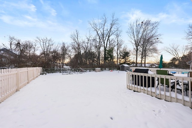 snowy yard with a shed and a deck