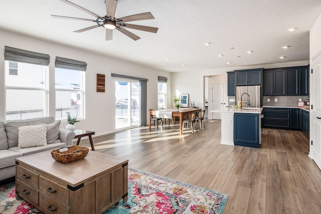 living room featuring ceiling fan, sink, and hardwood / wood-style flooring