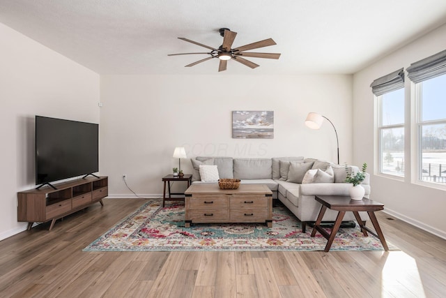 living room featuring ceiling fan, dark wood-type flooring, and plenty of natural light