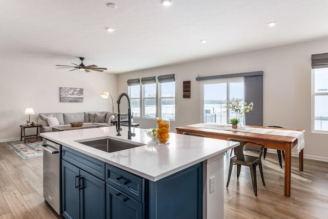 kitchen with sink, ceiling fan, light hardwood / wood-style floors, blue cabinetry, and a kitchen island with sink