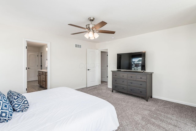 bedroom featuring light colored carpet, ceiling fan, and connected bathroom