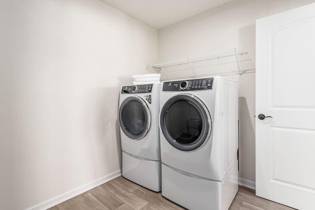 laundry area with washer and dryer and light hardwood / wood-style flooring