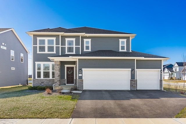 prairie-style home with aphalt driveway, an attached garage, stone siding, and a front lawn