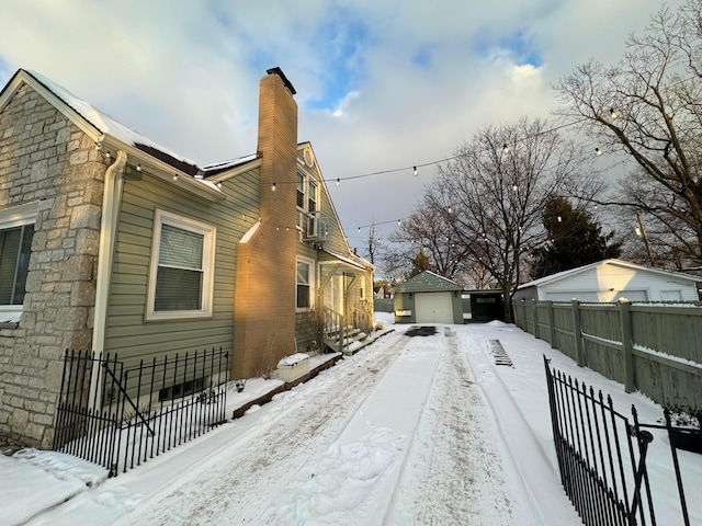 view of snow covered exterior with a garage and an outdoor structure