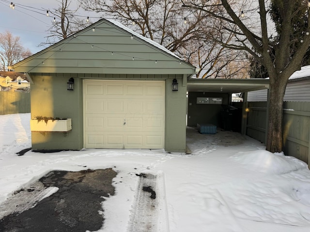 snow covered garage featuring a carport