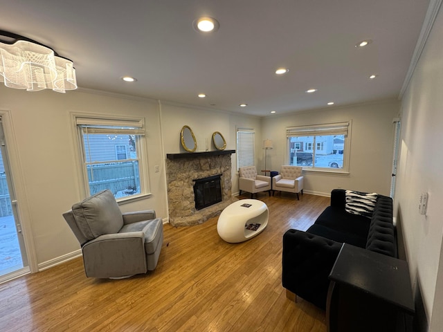 living room featuring hardwood / wood-style floors, a stone fireplace, and crown molding