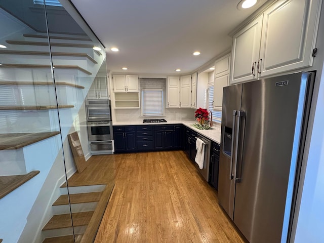 kitchen featuring white cabinets, sink, appliances with stainless steel finishes, tasteful backsplash, and light hardwood / wood-style floors