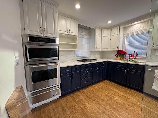 kitchen with blue cabinets, sink, light hardwood / wood-style flooring, white cabinetry, and stainless steel appliances