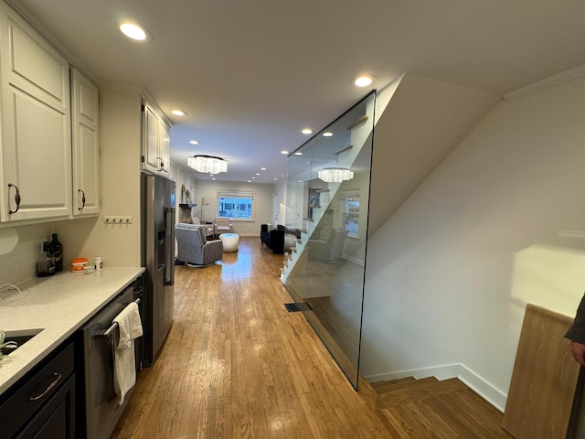 interior space featuring light stone counters, ornamental molding, stainless steel appliances, light hardwood / wood-style flooring, and white cabinetry