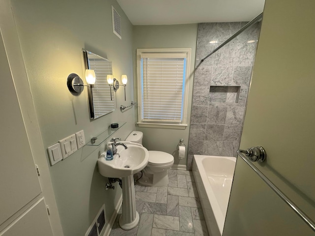 full bathroom featuring tiled shower / bath combo, toilet, and sink