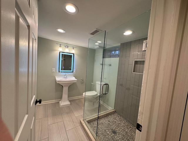 bathroom with a shower with door and toilet