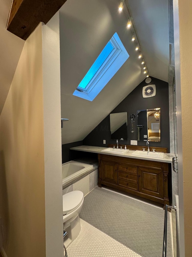 bathroom featuring vanity, lofted ceiling with skylight, a relaxing tiled tub, ceiling fan, and toilet