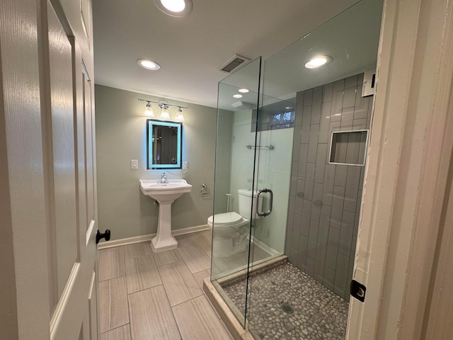 bathroom with a shower with shower door and toilet