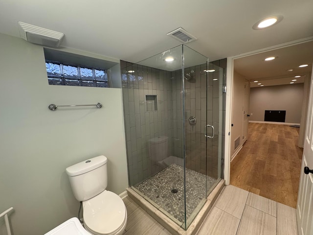 bathroom with an enclosed shower, toilet, and hardwood / wood-style floors