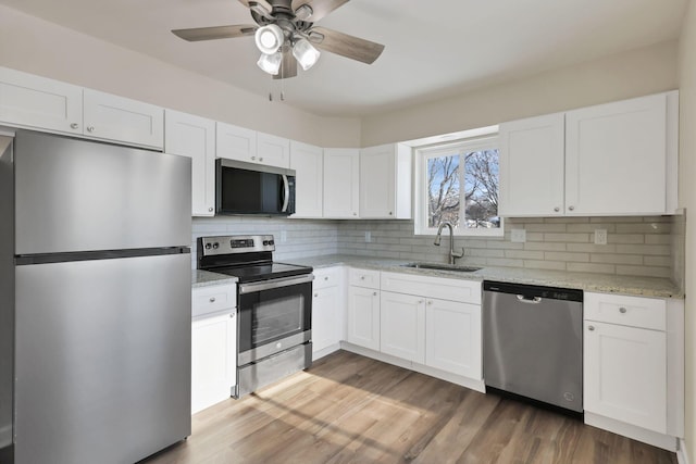 kitchen featuring light stone countertops, sink, stainless steel appliances, tasteful backsplash, and white cabinets