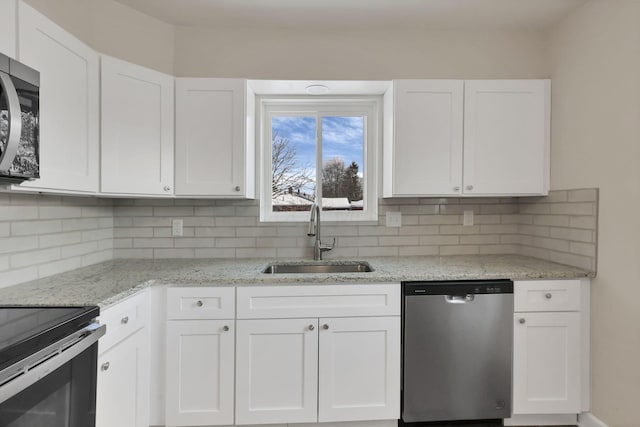 kitchen featuring light stone countertops, appliances with stainless steel finishes, backsplash, sink, and white cabinets