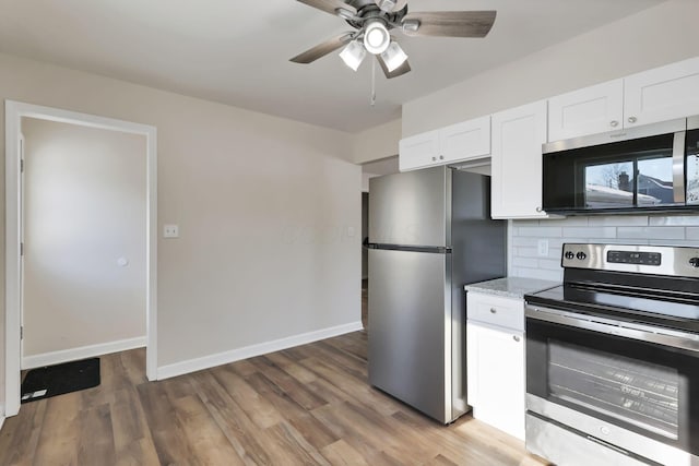 kitchen with light stone countertops, appliances with stainless steel finishes, decorative backsplash, white cabinets, and hardwood / wood-style flooring