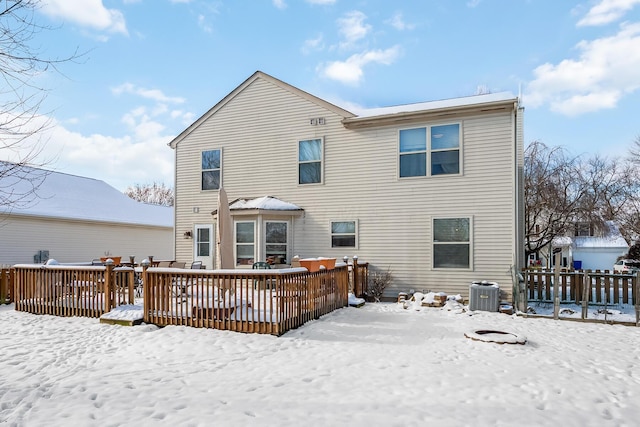 snow covered house with a deck and central air condition unit