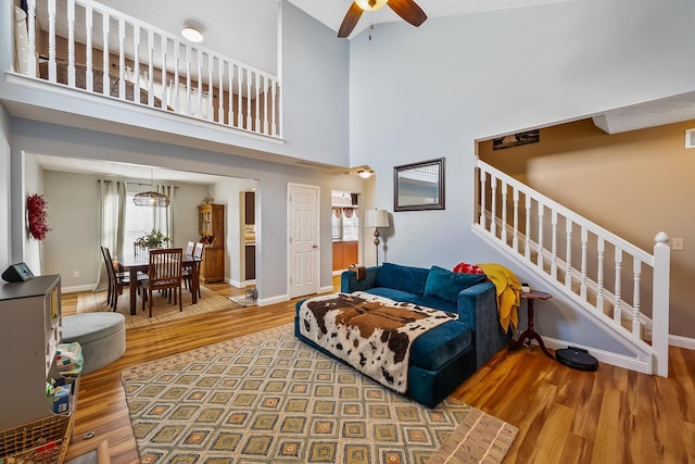 living room with ceiling fan, a high ceiling, and hardwood / wood-style flooring