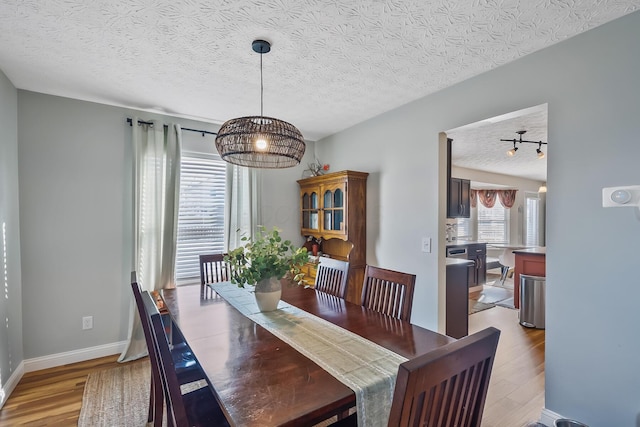 dining area featuring a textured ceiling, light hardwood / wood-style floors, and an inviting chandelier