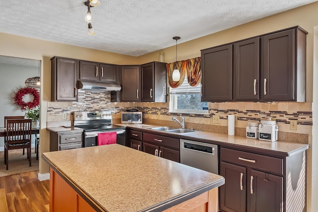 kitchen featuring appliances with stainless steel finishes, dark hardwood / wood-style flooring, a textured ceiling, sink, and decorative light fixtures