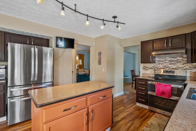 kitchen featuring appliances with stainless steel finishes, tasteful backsplash, a textured ceiling, dark wood-type flooring, and a center island