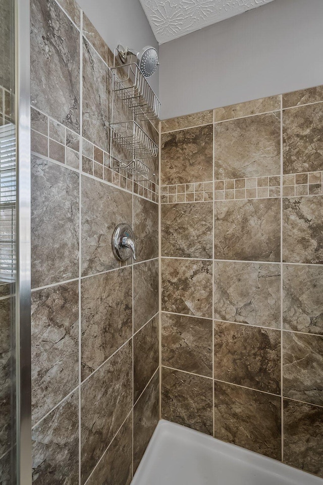 interior details with a tile shower and a textured ceiling