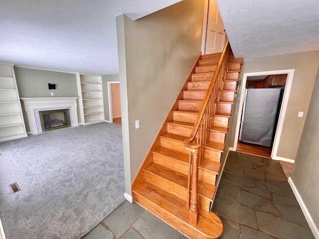 stairway with built in features, carpet floors, and a textured ceiling