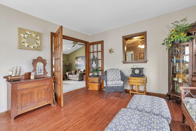 sitting room featuring french doors, light hardwood / wood-style floors, and vaulted ceiling