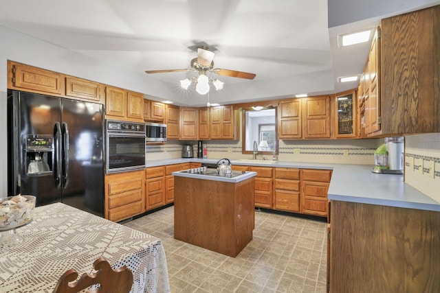 kitchen with decorative backsplash, a center island, ceiling fan, and black appliances