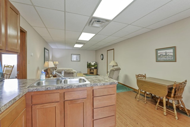 kitchen featuring a paneled ceiling, light wood-type flooring, and sink