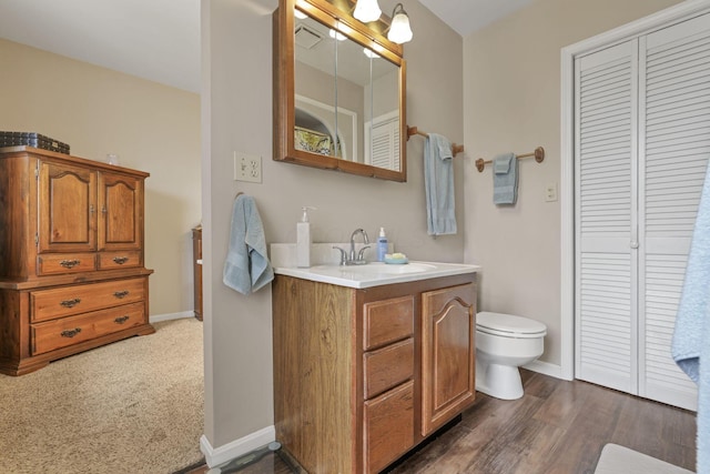 bathroom with wood-type flooring, vanity, and toilet