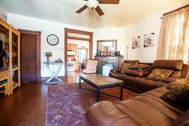 living room with ceiling fan, dark wood-type flooring, and a textured ceiling